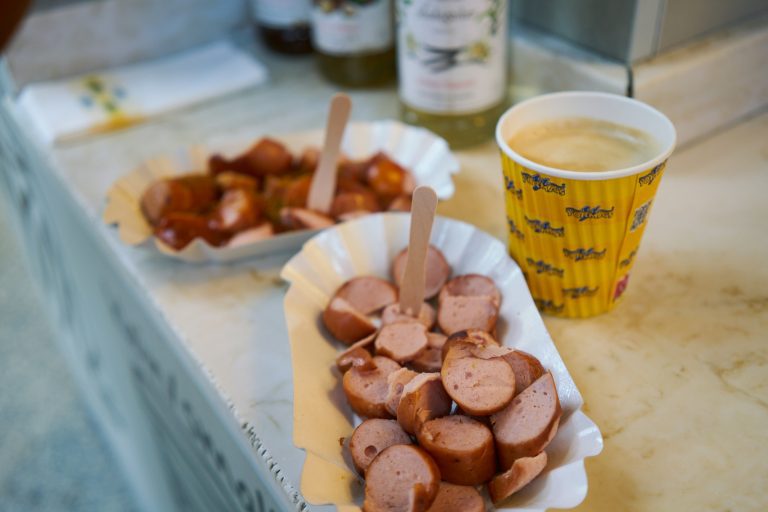 Sliced currywurst with sauce and coffee in a paper cup at snack counter
