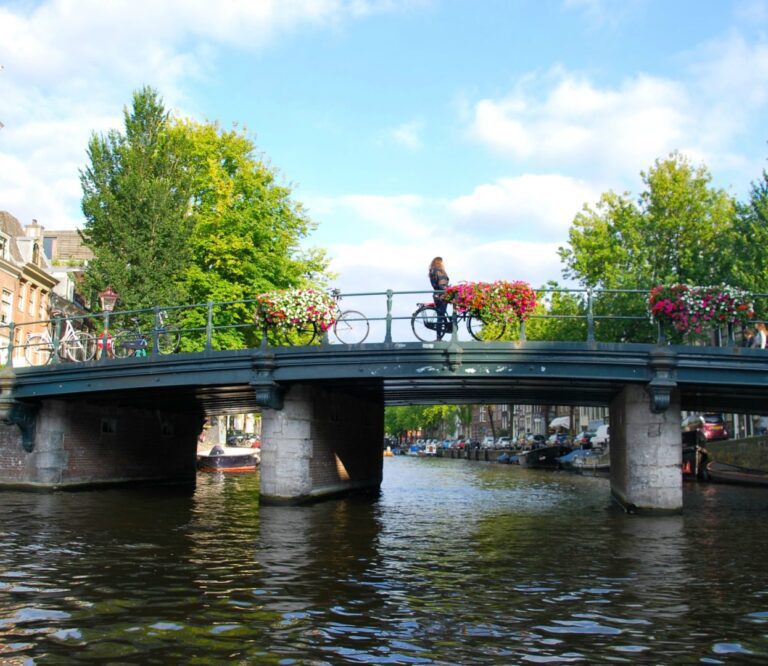 Biking over a flower-covered canal bridge in Amsterdam