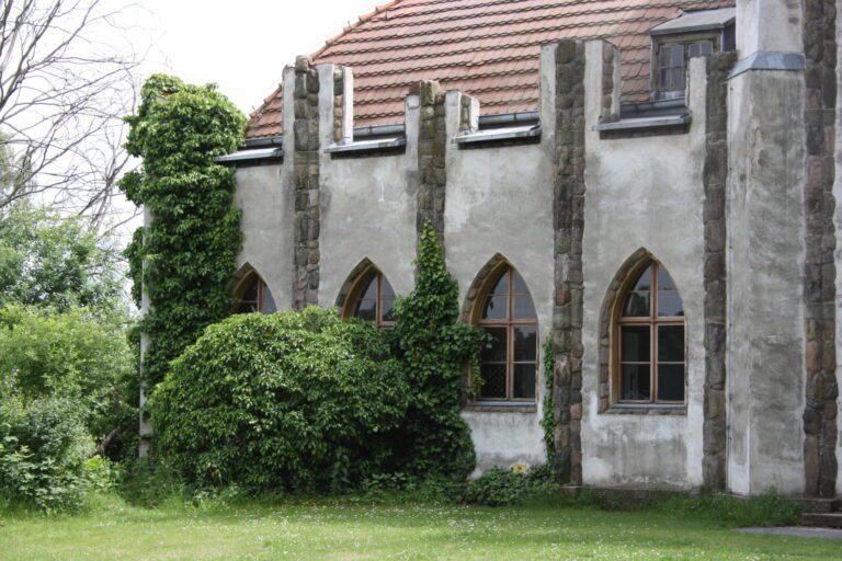 Green ivy covers a part of the church with arched windows and stone columns