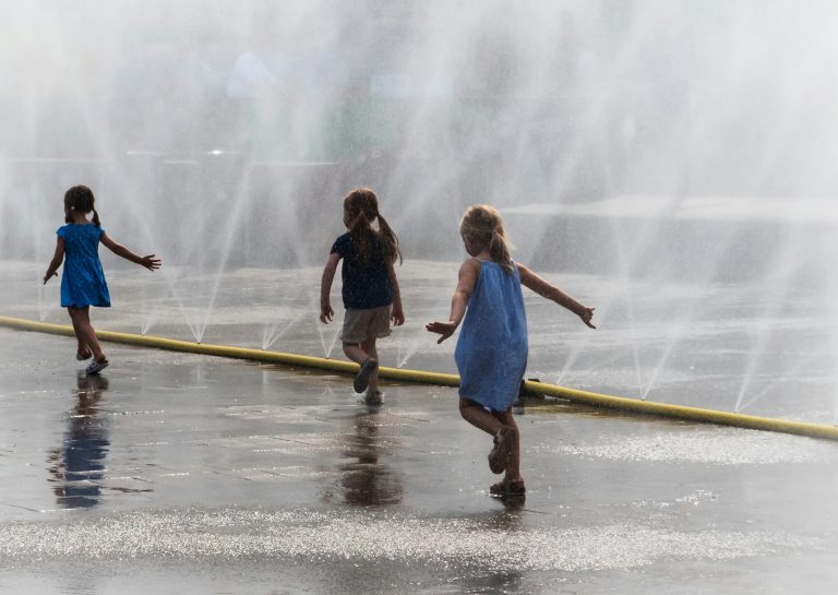 Three kids playing inside a fountain