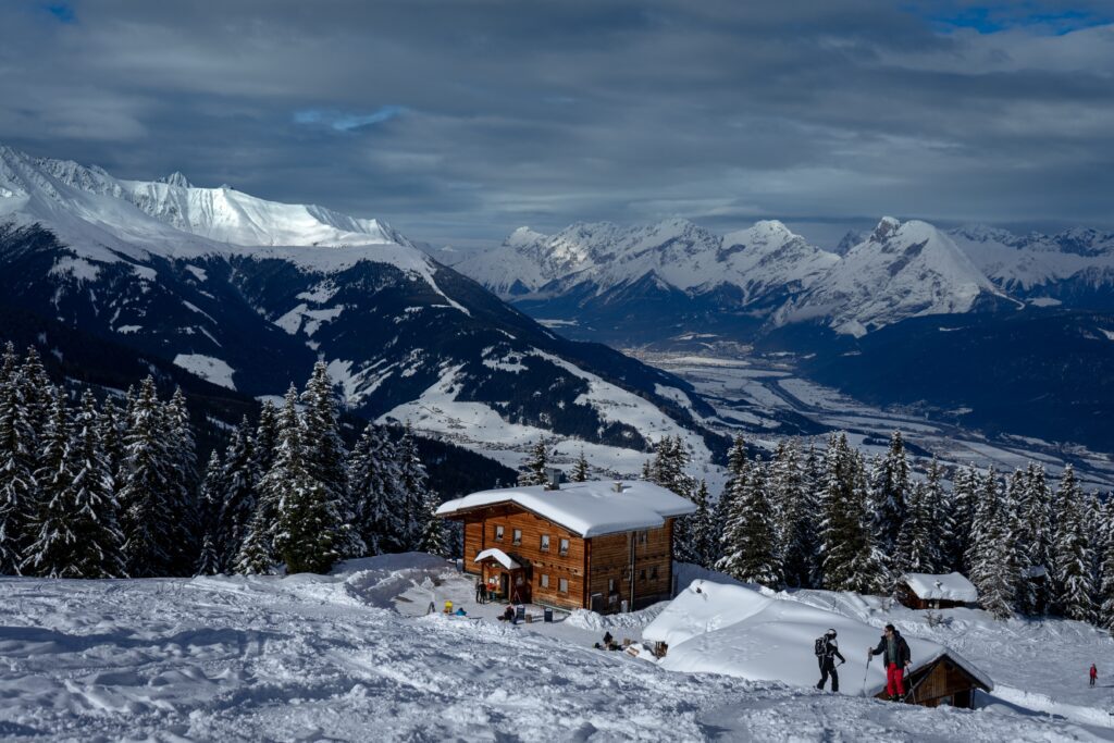 Familienfreundliche Skigebiete bei Innsbruck - Ein Panoramablick auf verschneite Berge und ein Holzhaus