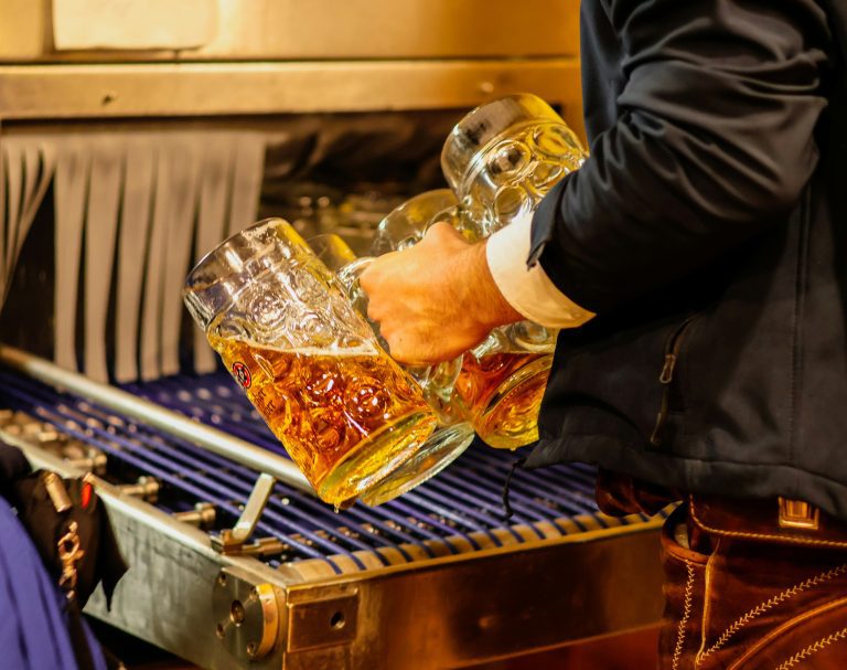 Man carrying large beer mugs filled with amber beer at Munich Oktoberfest
