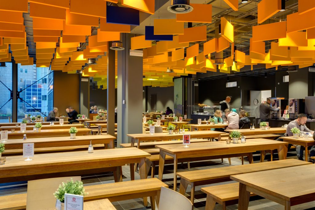 Gemütlicher Speisesaal mit Holztischen und leuchtend oranger Decke