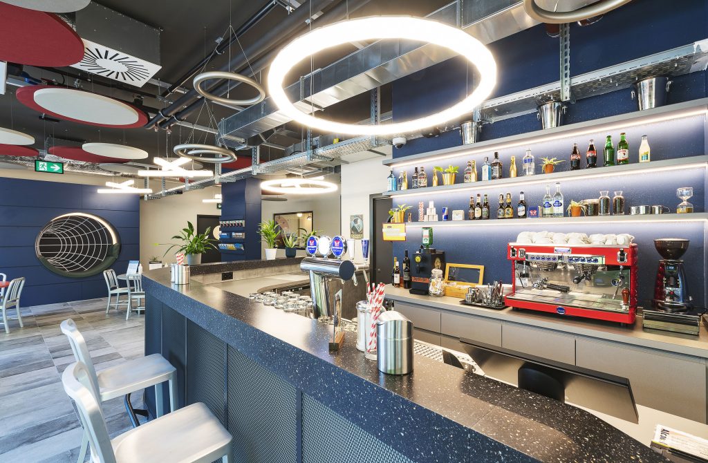 Modern hotel bar with stylish seating, drinks display, and coffee machine