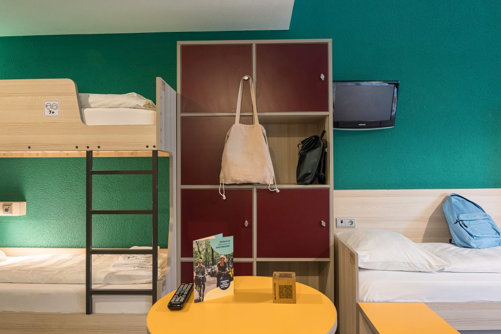 Bunk beds and lockers in a shared room with travel gear and guide