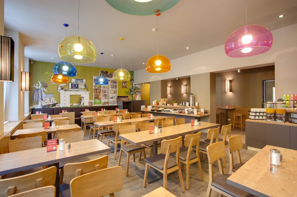Colorful breakfast room with long tables at MEININGER Hotel