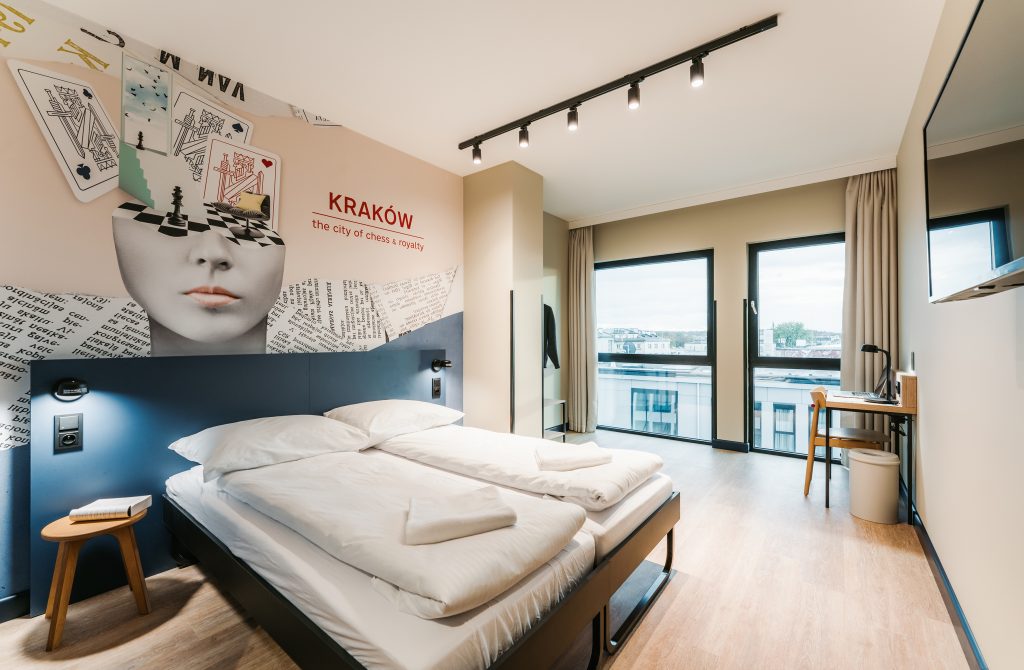 Stylish MEININGER Kraków Centrum room with chess-themed wall art and cozy bed
