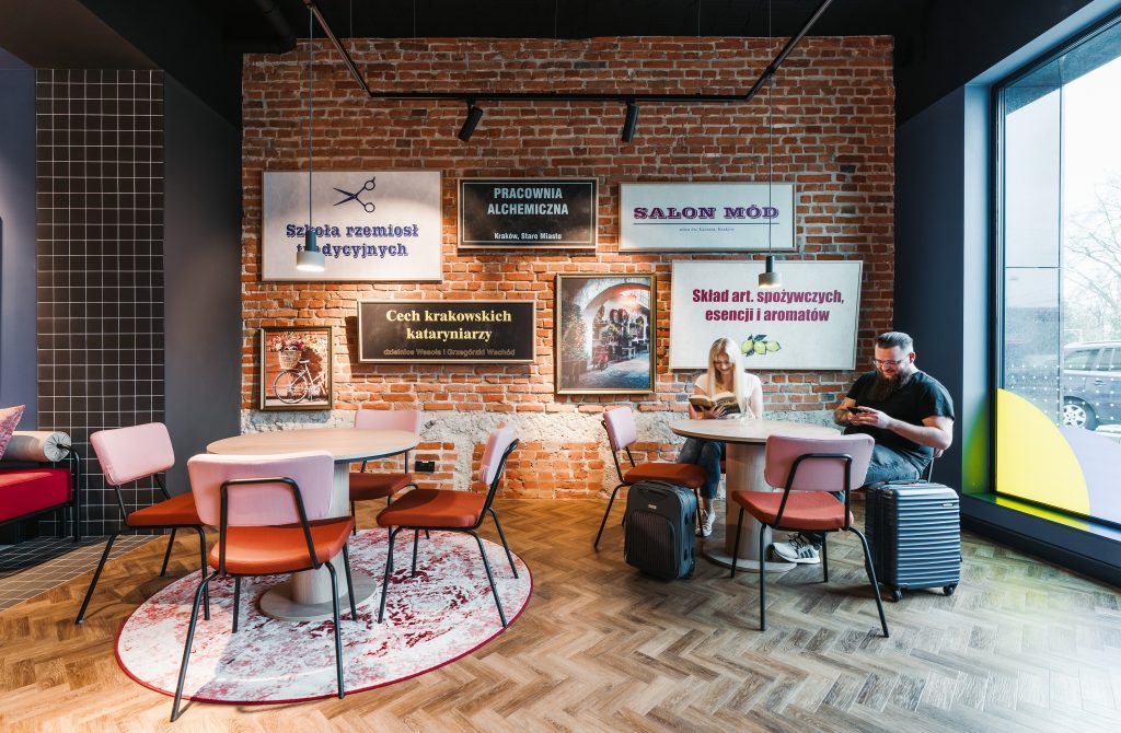 Cozy MEININGER Kraków Centrum lobby with brick walls, posters, and chill vibes