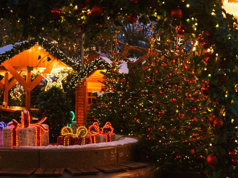 Cozy Christmas market with trees, lights, and glowing gift decorations at night