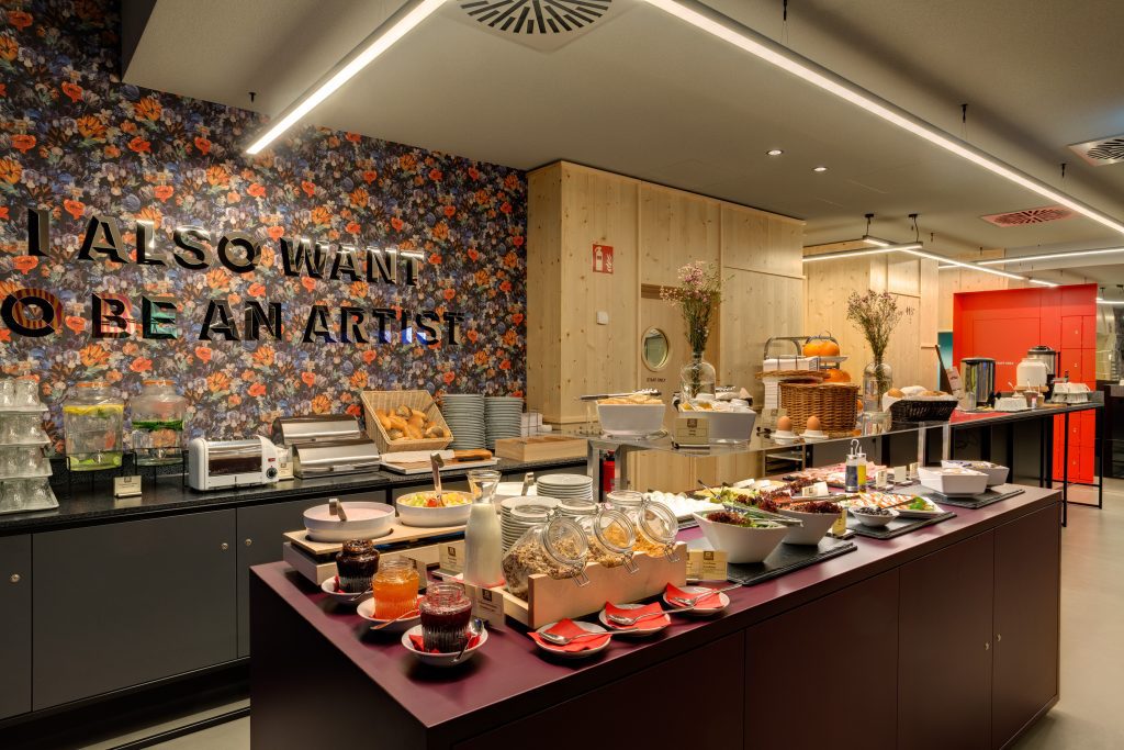 Buntes Frühstücksbuffet mit cooler Deko und künstlerischer Wand