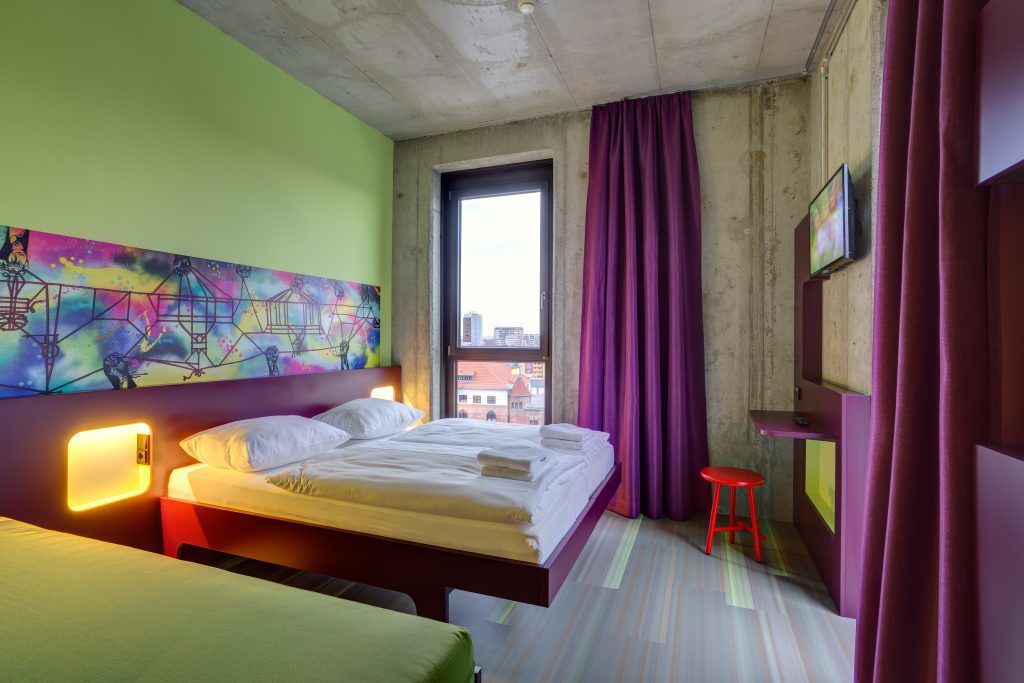 Helles Hotelzimmer mit Stadtblick und buntem Design im MEININGER Hotel Berlin East Side Gallery 