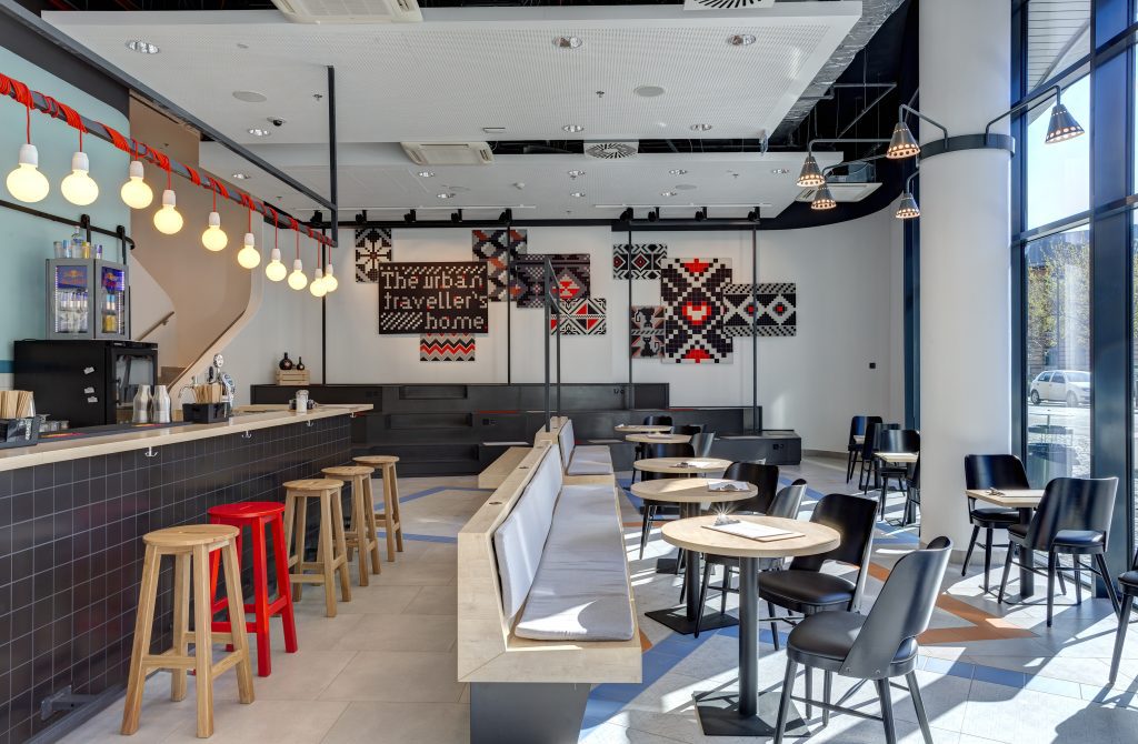 Moderne Hotelbar mit Hockern und viel Tageslicht im MEININGER Budapest Great Market Hall 