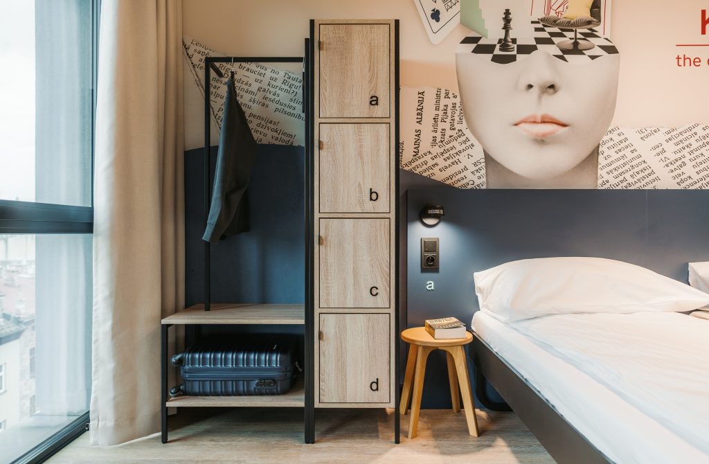 Private room with a wooden wardrobe, a twin bed and wall decor at MEININGER Hotel Kraków Centrum