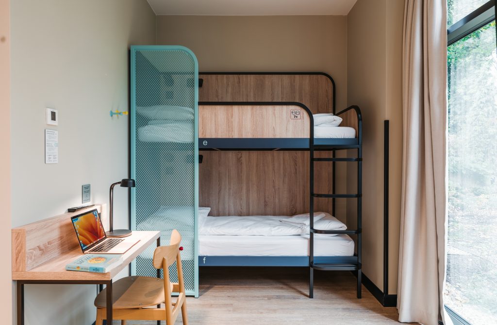 A wooden bunk bed and a desk in a shared dormitory at MEININGER Hotel Kraków Centrum
