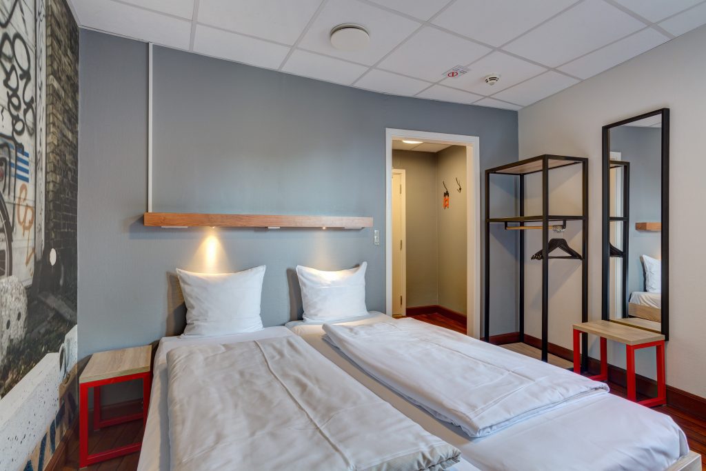 Doppelzimmer mit Doppelbett, Wanddeko, Kleiderständer und Spiegel