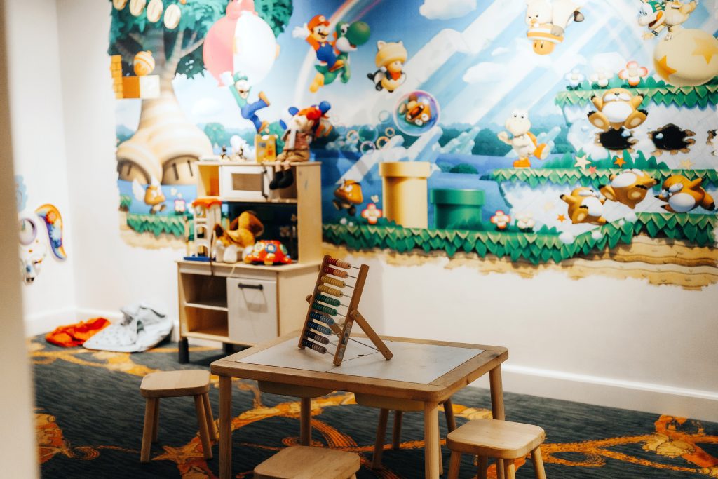 Children’s playroom with toys, table, and Mario-themed wall mural