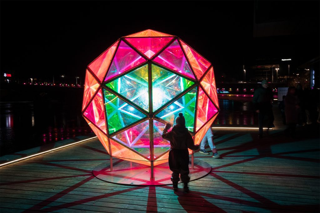 Light festival Copenhagen: Kid admiring a glowing rainbow dome at Copenhagen Light Festival