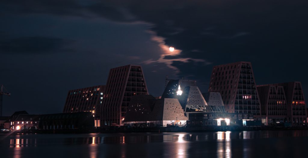 Light festival Copenhagen: the city skyline on the river in the night with the moon on the background