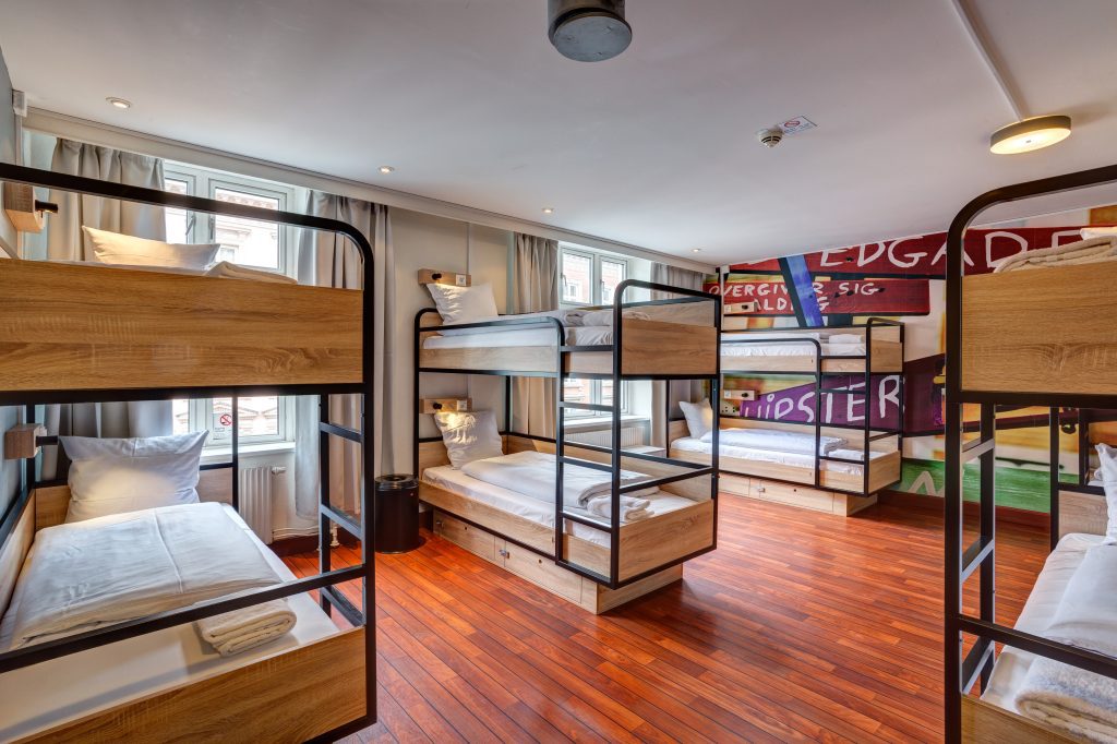 Room with six wooden bunk beds and graffiti-style wall art