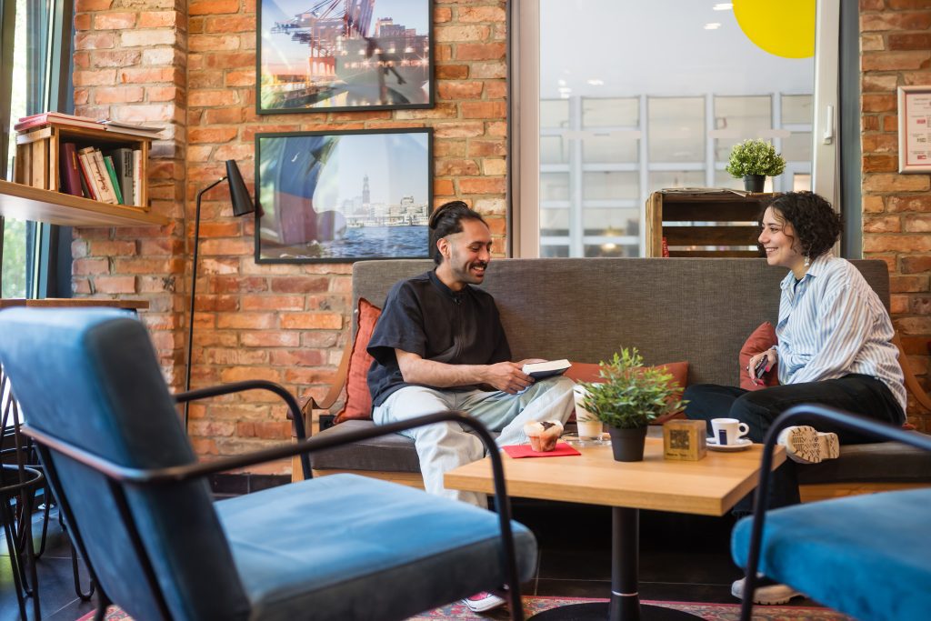 MEININGER Hotel Hamburg City Center two people sitting on sofa with coffee, talking