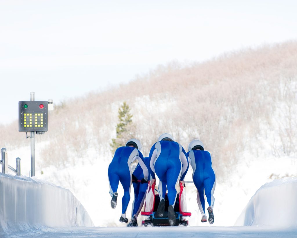 Winter olympics Italy: Bobsleigh team in blue suits pushing off on an icy track during a winter race