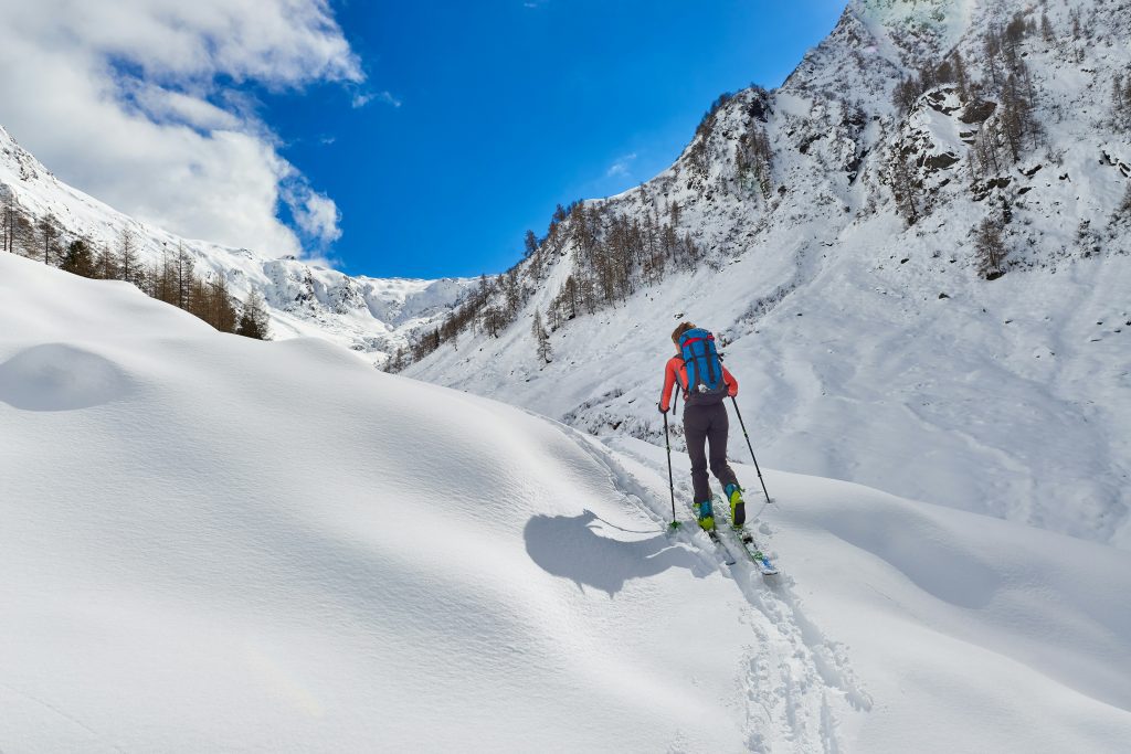 Winter olympics Italy: Skier climbing up snowy mountain for ski mountaineering in the Italian Alps