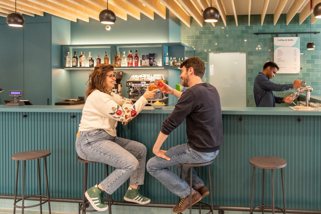 Couple toasting drinks at the hotel bar with teal tiles