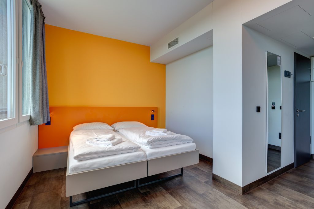 MEININGER Hotel Munich Olympiapark: camera con due letti singoli e pareti arancioni