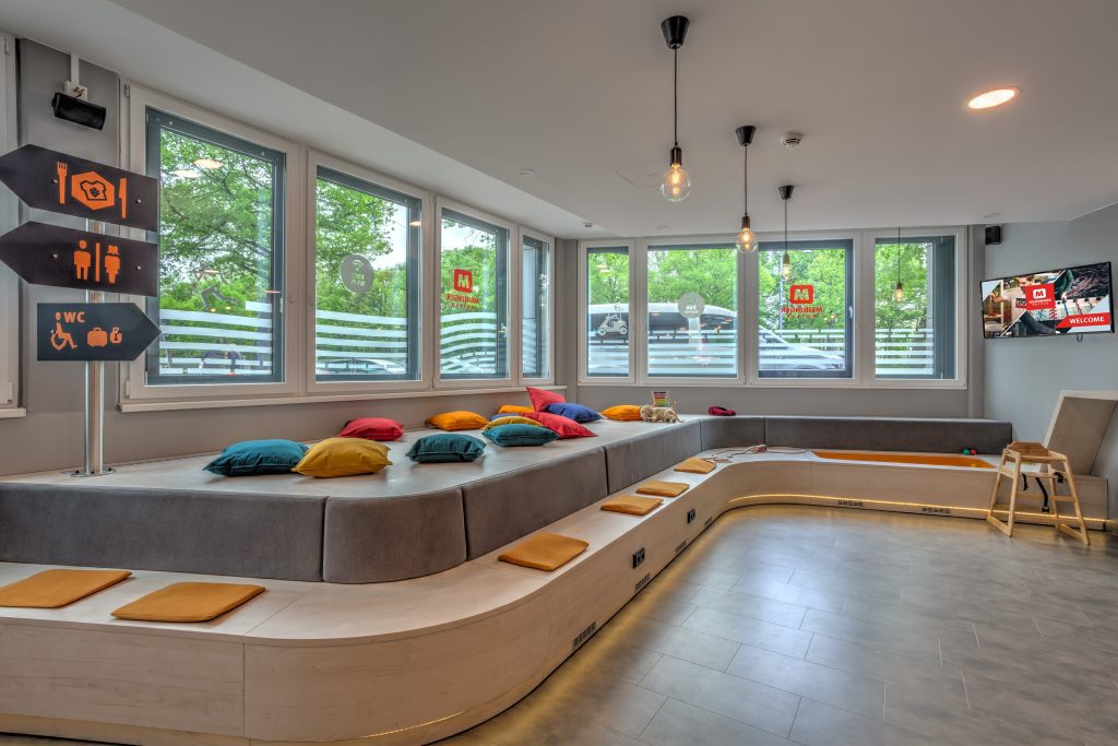 MEININGER Hotel Munich Olympiapark: area relax con panca/divano lungo e cartelli di orientamento