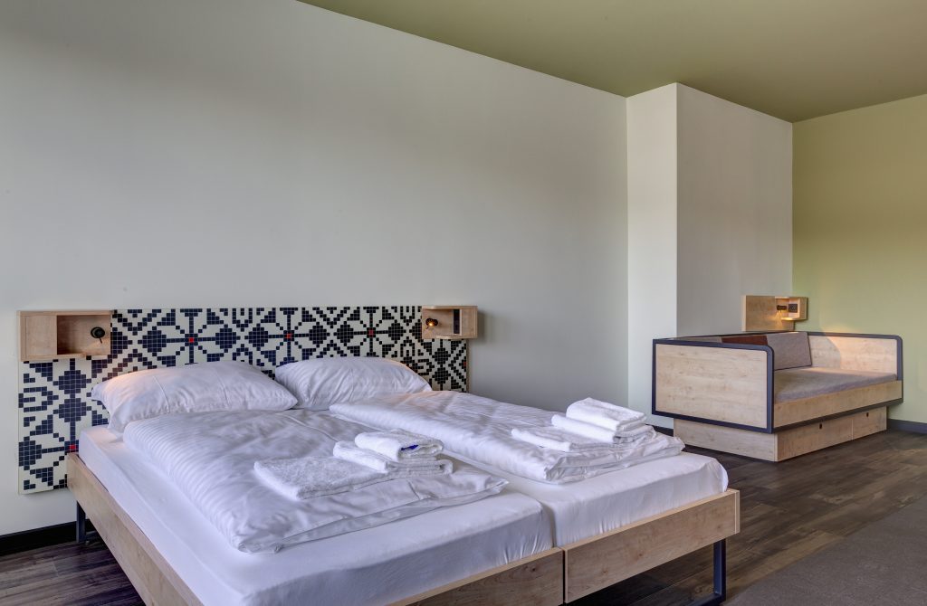 Camera con letto doppio con decorazione sulla testiera e culla in legno