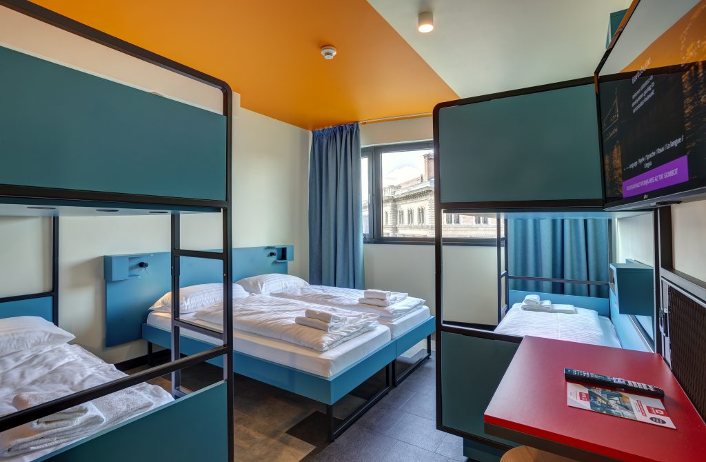 Dormitorio con letti singoli e a castello in legno blu e tavolino rosso