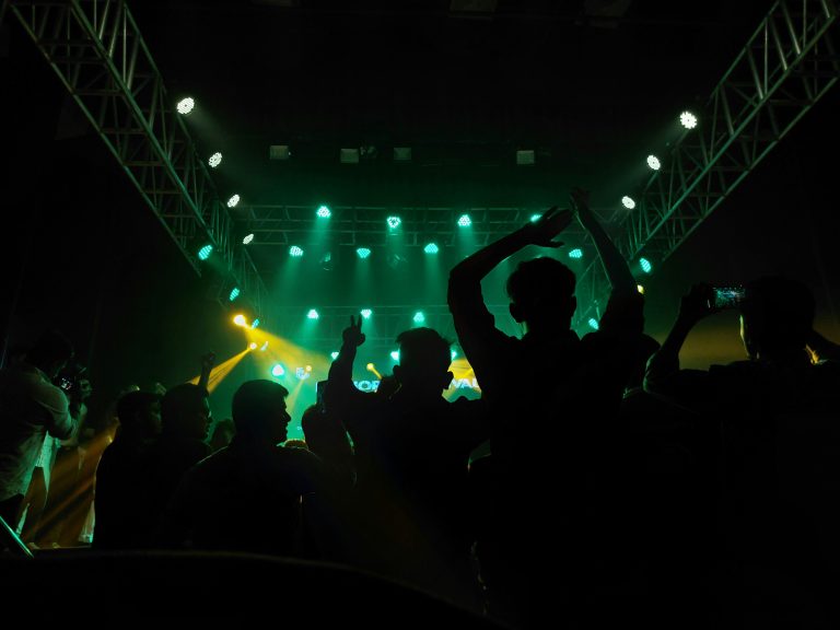 A concert crowd from the back in the dark with green lights