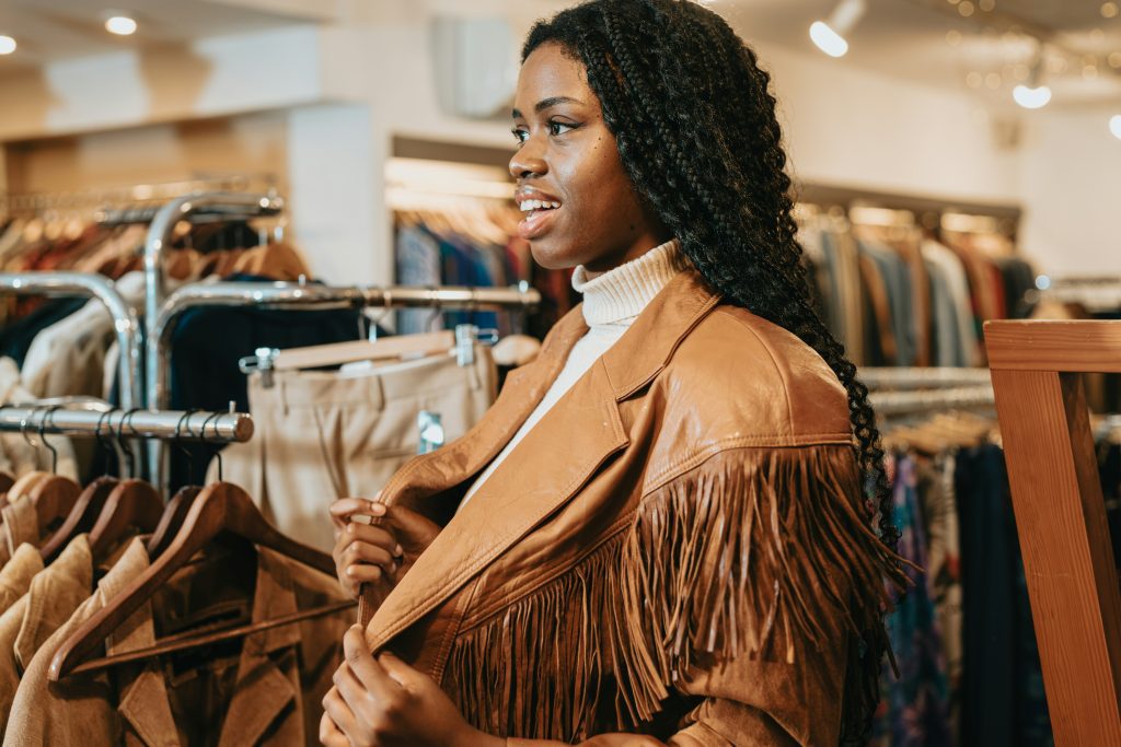 Shopping in Barcelona: Frau probiert Lederjacke mit Fransen im Vintage-Shop an