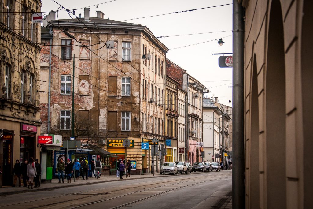 Busy street in Krakow's Kazimierz district with local shops and tram lines