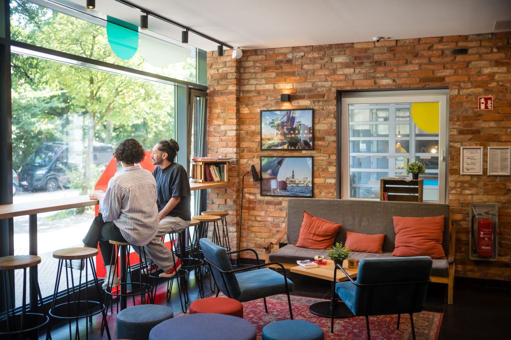 Cozy hotel lounge with seating and people by large windows
