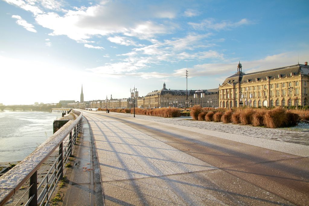 Surfen Bordeaux: Promenade am Flussufer von Bordeaux mit historischen Gebäuden bei Sonnenuntergang