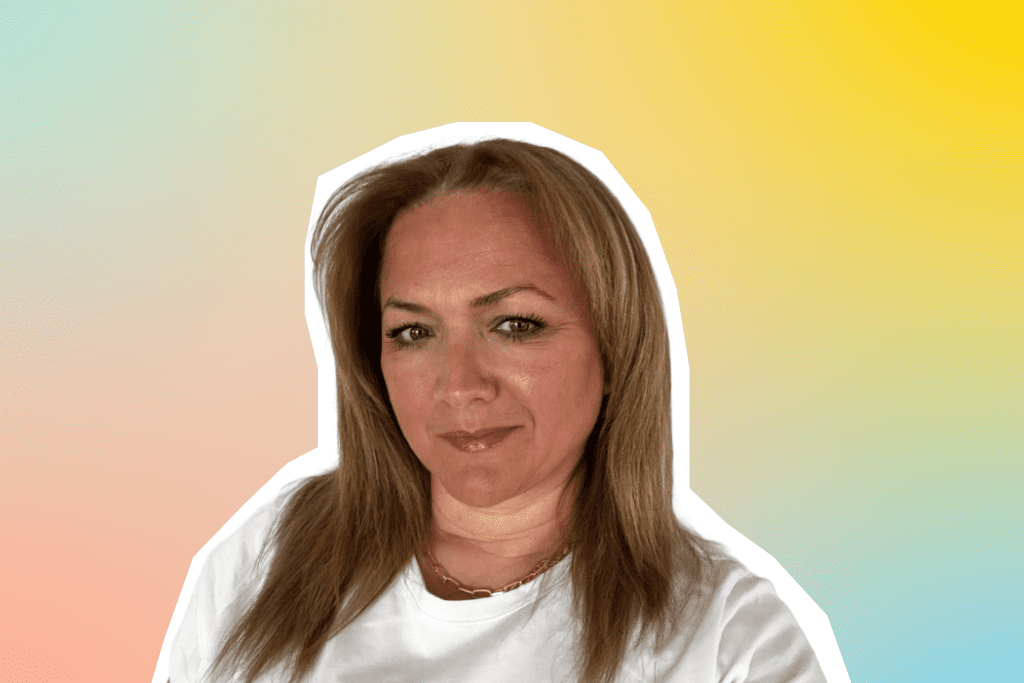 Ein Porträt von Daniela, Regionaldirektorin bei MEININGER Hotels, vor einem farbenfrohen Hintergrund