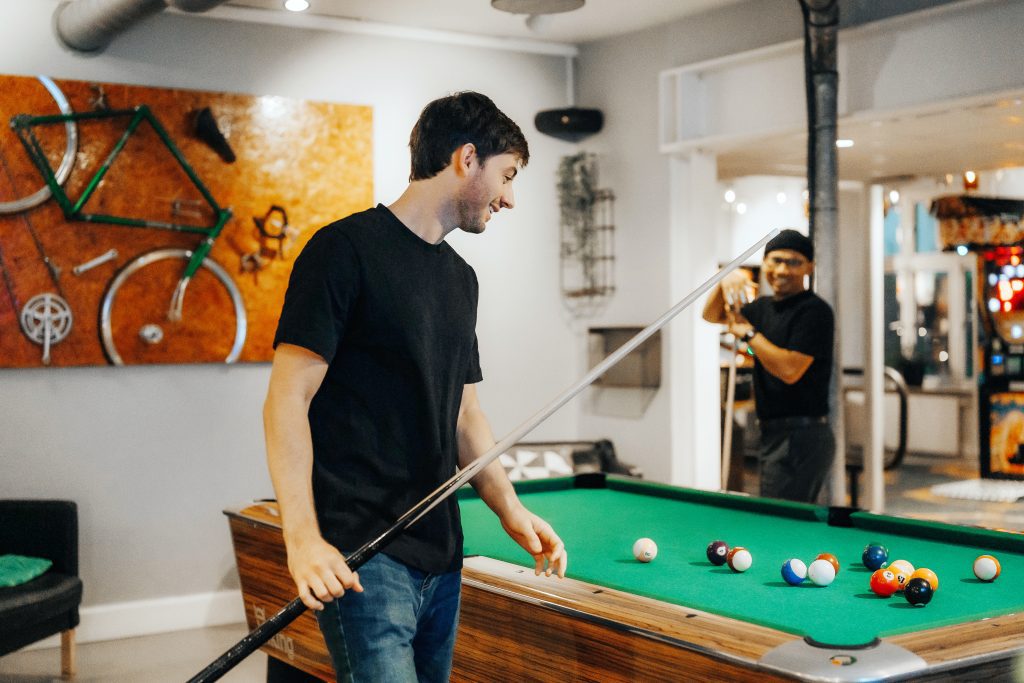 Guest playing pool in the games room at MEININGER Hotel Copenhagen, with a bike-themed wall art piece in the background
