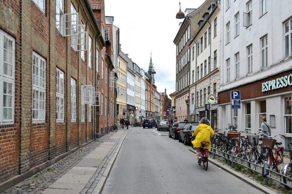 Fahrradverleih in Kopenhagen: Frau fährt mit dem Fahrrad durch eine historische Straße in Kopenhagen