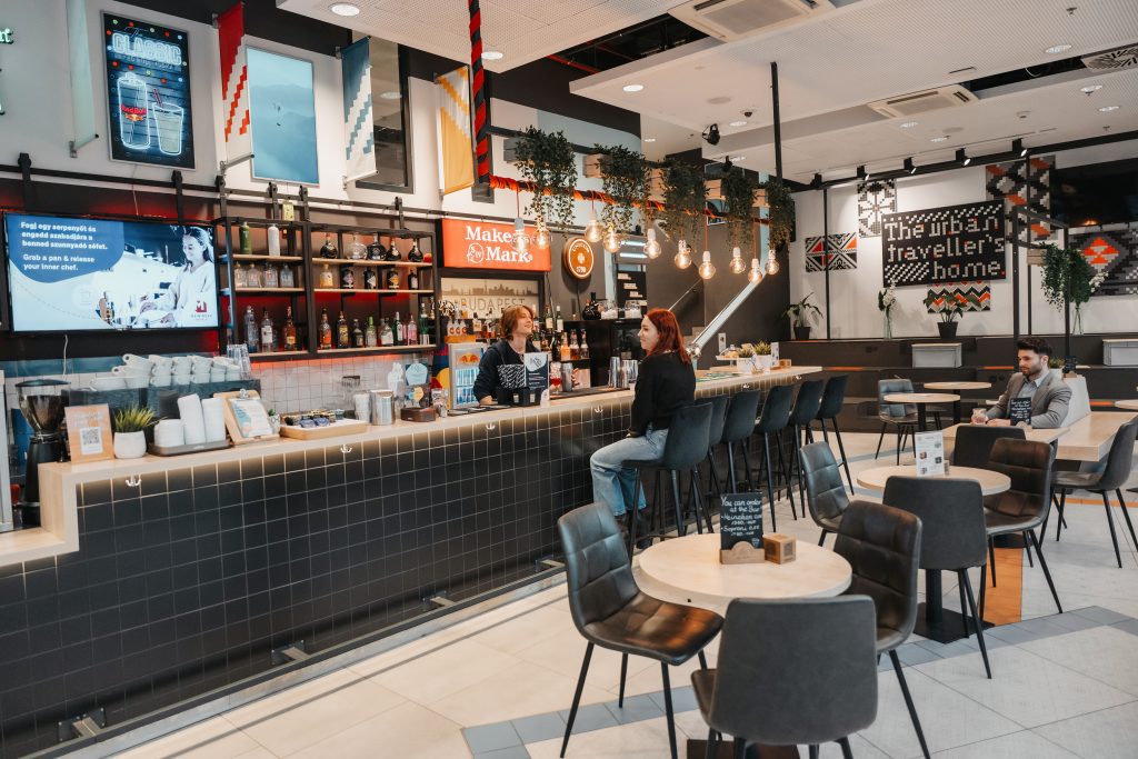 Hotel bar with high stools, dark counter and screens on the wall