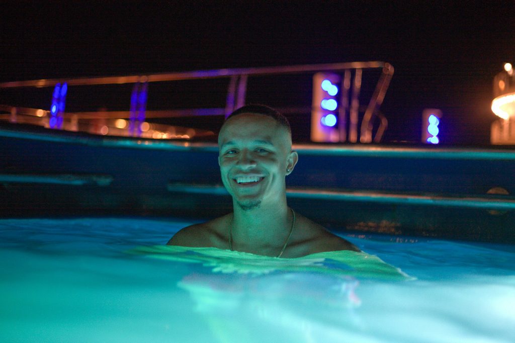 Person smiling in illuminated pool at Széchenyi Baths party at night