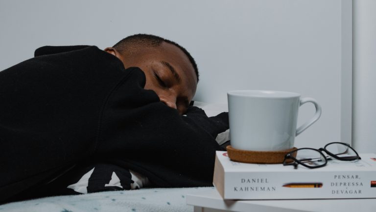 A man sleeping near a book and a cup of tea