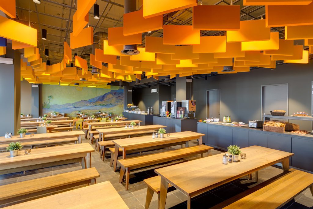 Bright breakfast area at MEININGER Hotels Amsterdam with wooden tables