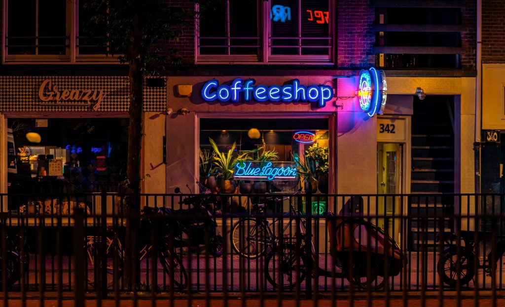 Fun facts Amsterdam: Coffee shop with neon signs and plants in the window