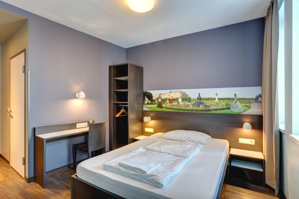 Privates Doppelzimmer mit warmem Licht, Holzmöbeln und Schönbrunn-Wandbild