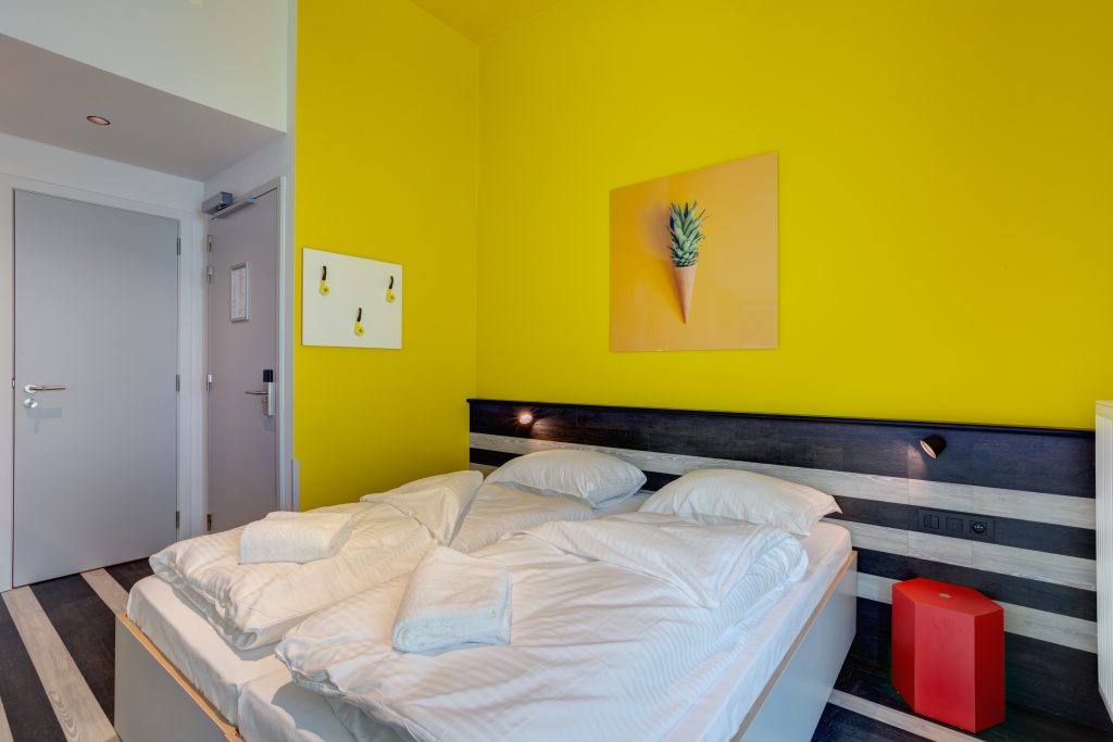 Bright double room with yellow wall and comfy bed