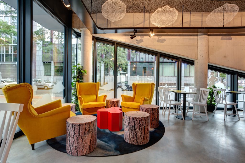 Cozy hotel lounge with yellow armchairs and tree stump tables