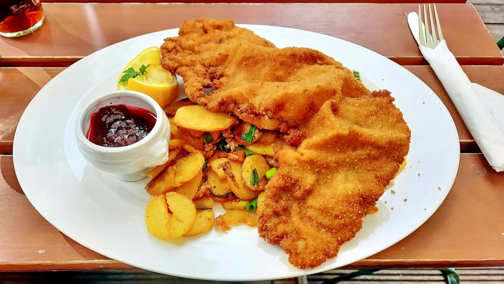 Cosa mangiare a Vienna: croccante Wiener Schnitzel con patate fritte, limone e salsa di mirtilli rossi
