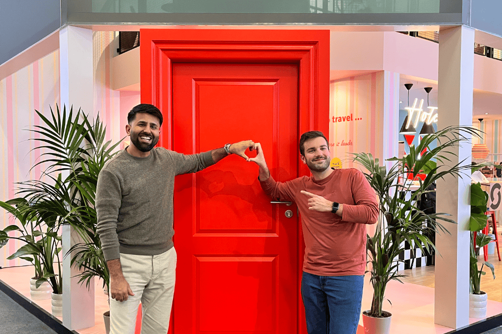Ismail and Emiliano at the ITB 2026 making a heart sign with their hand on a red door at the MEININGER booth
