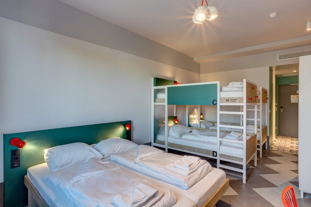 Green dorm room with a double bed and bunk beds